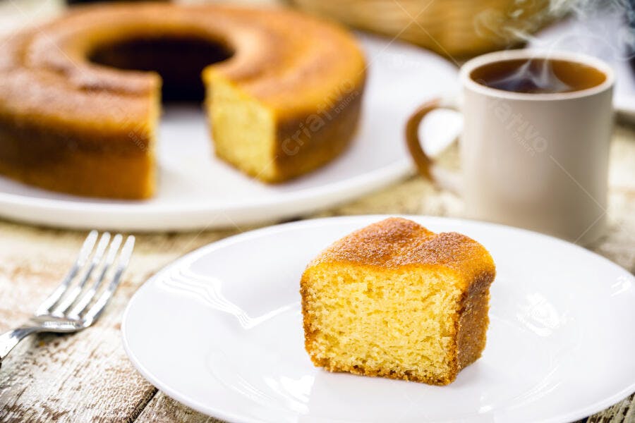 Bolo de fubá com fatia em prato branco e café fumegante