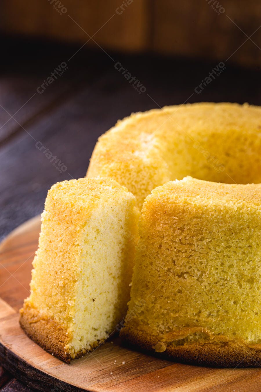 Bolo caseiro amarelo em fatias sobre tábua de madeira escura