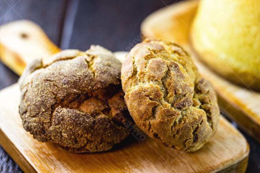 Pães de milho caseiros dourados em tábua de madeira rústica