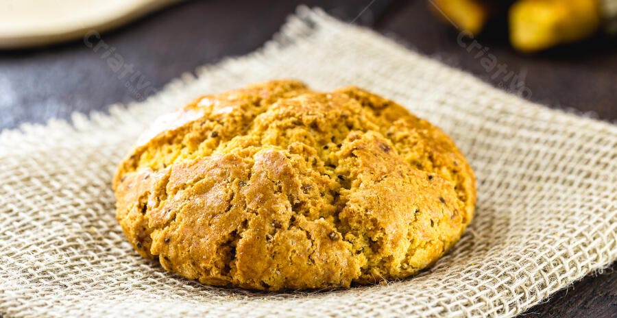 Pão rústico artesanal dourado sobre tecido de juta em fundo escuro
