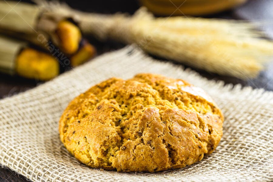 Biscoito rústico dourado sobre juta com espigas de trigo em fundo desfocado