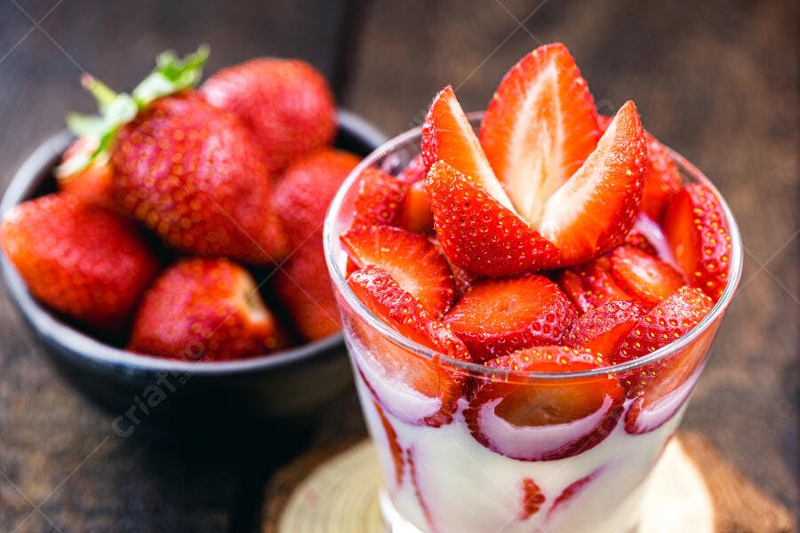 Morangos frescos com creme em copo e tigela de frutas vermelhas