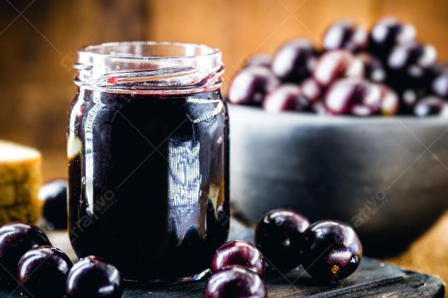 Jarra de geleia de jabuticaba escura com frutas frescas em madeira rústica