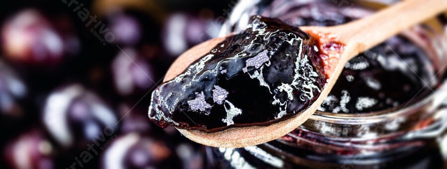 Geleia escura de frutas vermelhas em colher de pau close-up gourmet