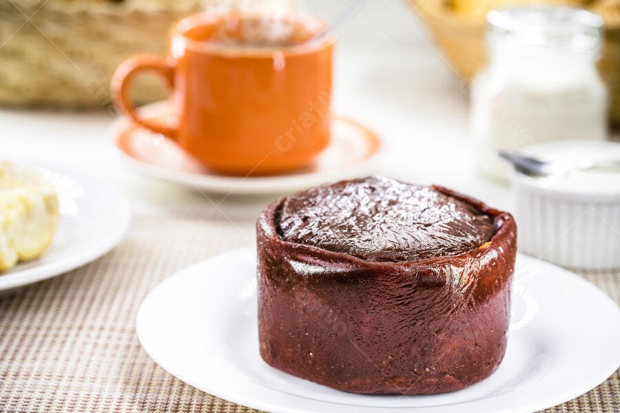 Bolo de chocolate individual em prato branco com café e mesa de café da manhã
