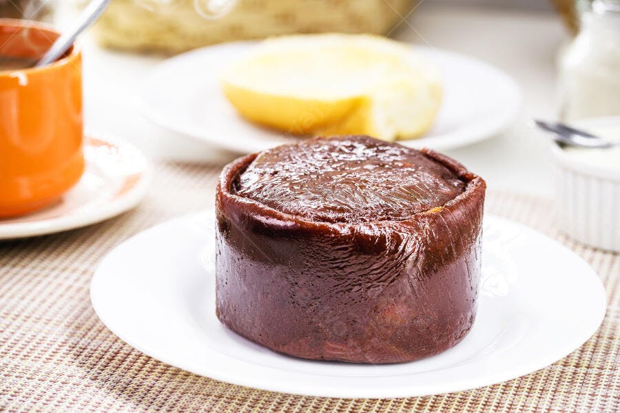 Bolo de rolo ou pudim escuro em prato branco para café da manhã ou lanche