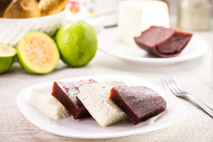 Goiabada e queijo minas frescos na mesa rústica com goiabas e pães