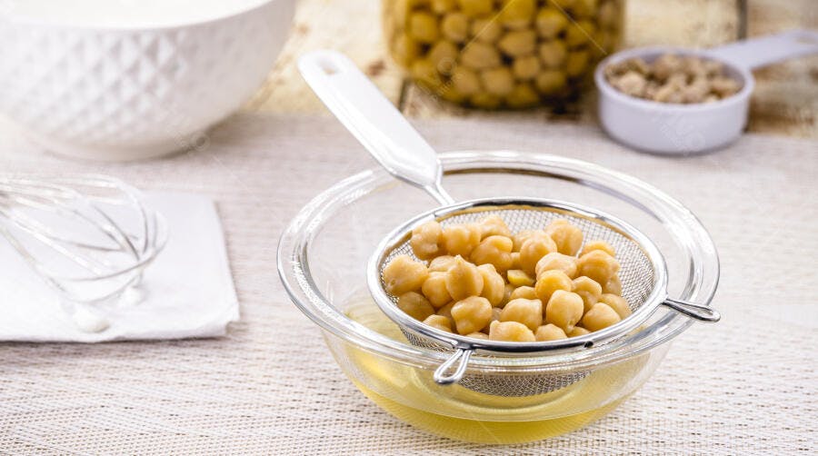 Grão de bico cozido escorrendo aquafaba em peneira de metal