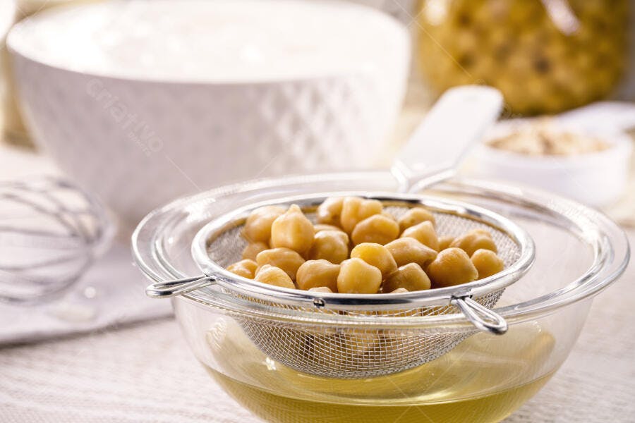 Grão de bico cozido escorrido em peneira sobre tigela com aquafaba