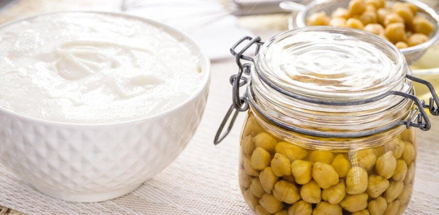Grão de bico em conserva e pasta de tahine para hummus em tigela branca