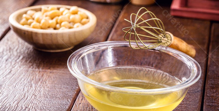 Aquafaba líquido e grão de bico em tigelas rústicas sobre madeira