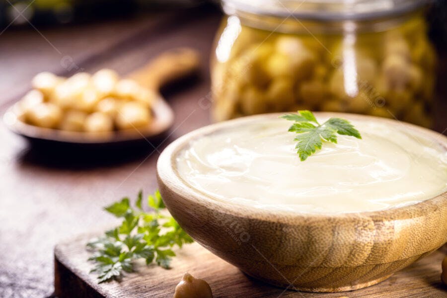Maionese cremosa em tigela de madeira com salsa e grão de bico