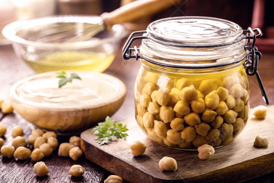 Grão de bico em frasco e homus cremoso com aquafaba em cozinha preparando alimentos saudáveis
