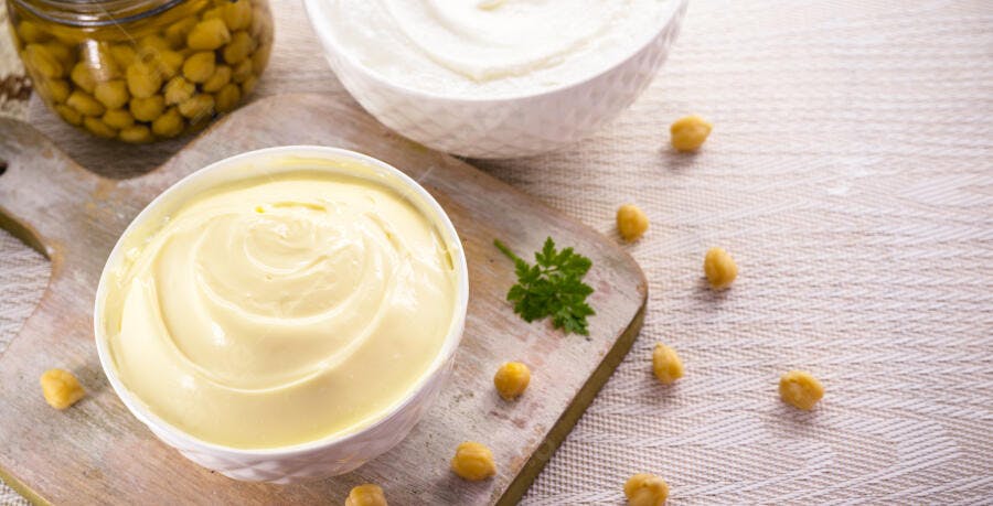 Molhos cremosos e grão de bico em tábua de madeira com salsa