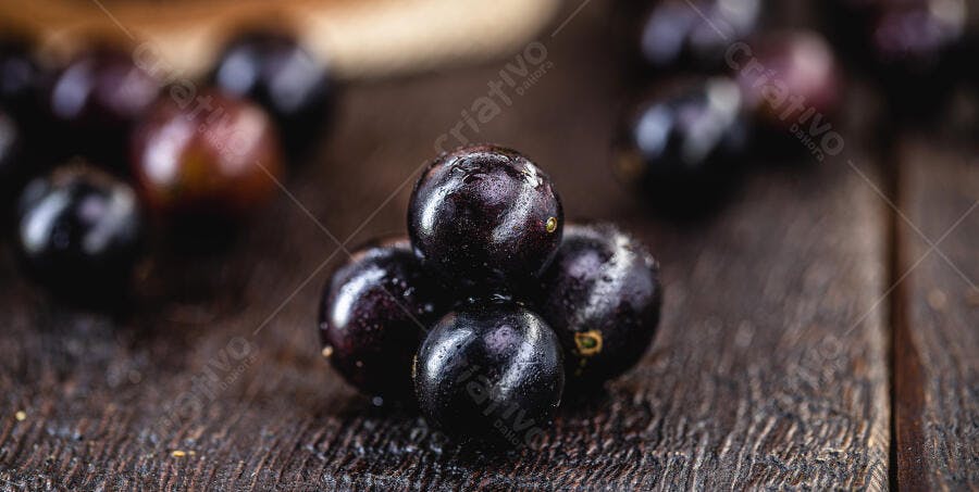 Jabuticabas frescas com gotas de água em madeira rústica escura