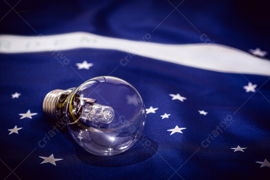Lâmpada incandescente sobre bandeira do Brasil azul escuro com estrelas brancas