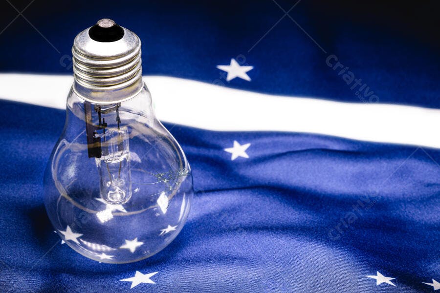 Lâmpada incandescente transparente sobre bandeira azul com estrelas brancas