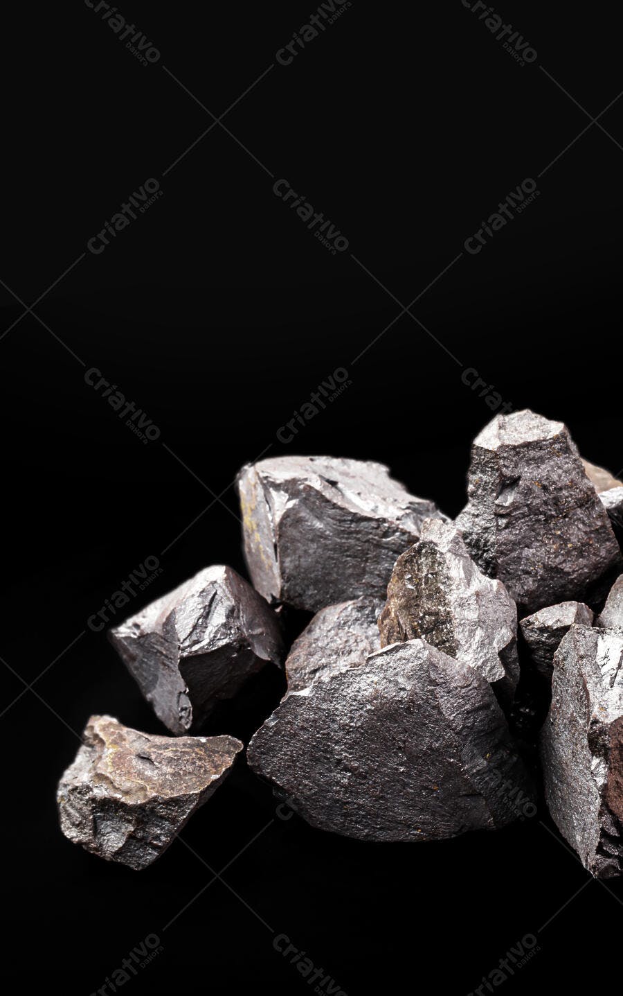 Minério de ferro bruto escuro em fundo preto com reflexos metálicos