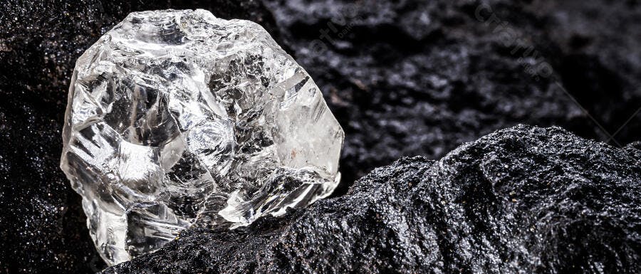 Cristal bruto transparente sobre rocha escura mineral