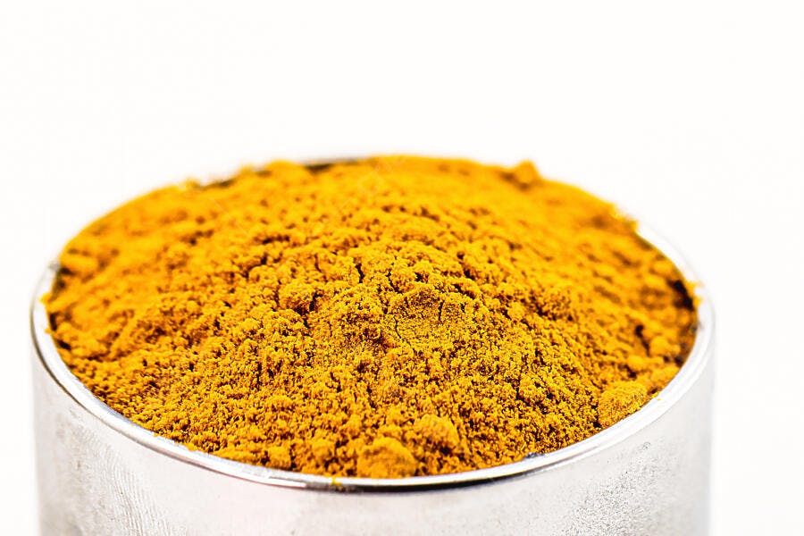 Cúrcuma em pó amarelo brilhante em pote metálico sobre fundo branco
