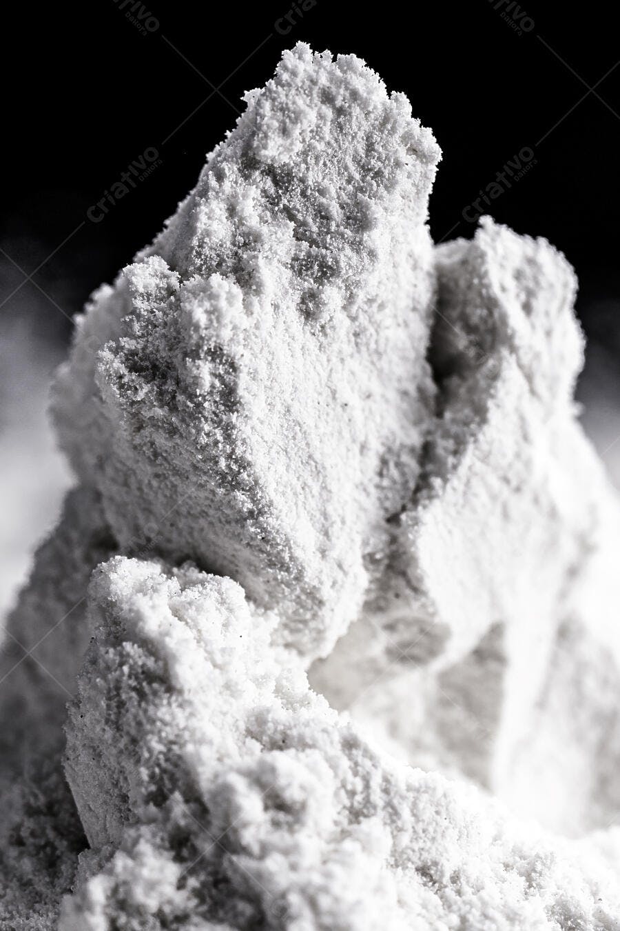 Pó branco cristalino em pilhas com textura granular e fundo escuro