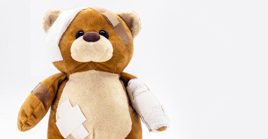 Urso de pelúcia marrom com curativos e ataduras em fundo branco