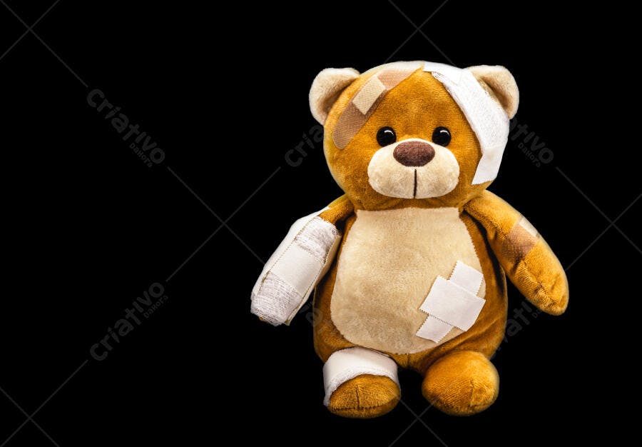 Urso de pelúcia marrom machucado com curativos em fundo preto