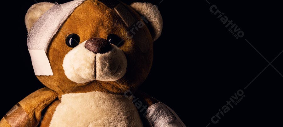 Urso de pelúcia marrom ferido com bandagens em fundo escuro