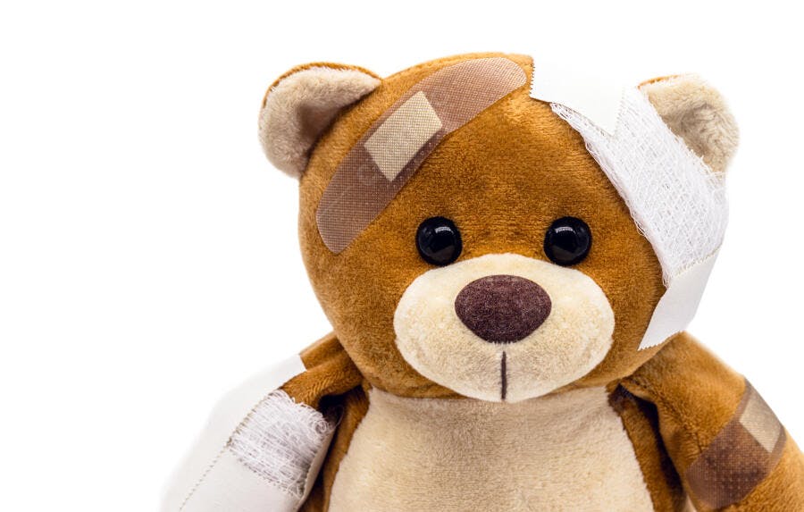 Urso de pelúcia marrom com curativos e bandagens em fundo branco isolado