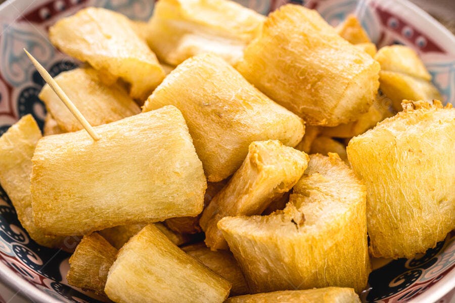 Mandioca frita crocante servida em tigela colorida com palito de dente