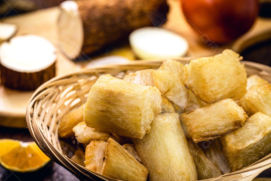 Mandioca frita dourada em cesto com ingredientes frescos na cozinha
