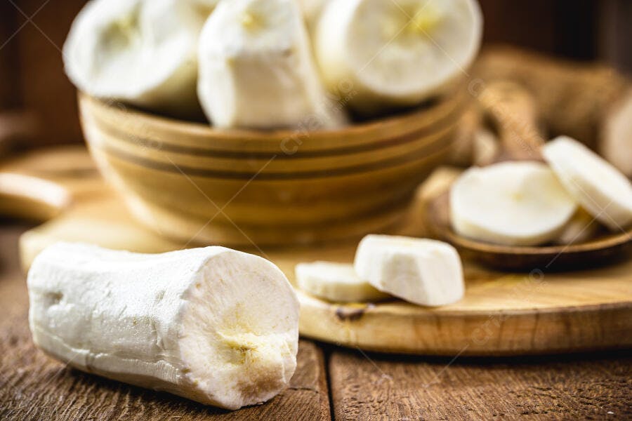 Mandioca Yuca Macaxeira crua em pedaços e fatias sobre tábua de madeira rústica
