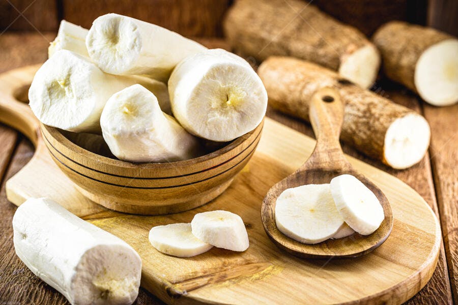 Mandioca crua e descascada em tigela de madeira com fatias frescas