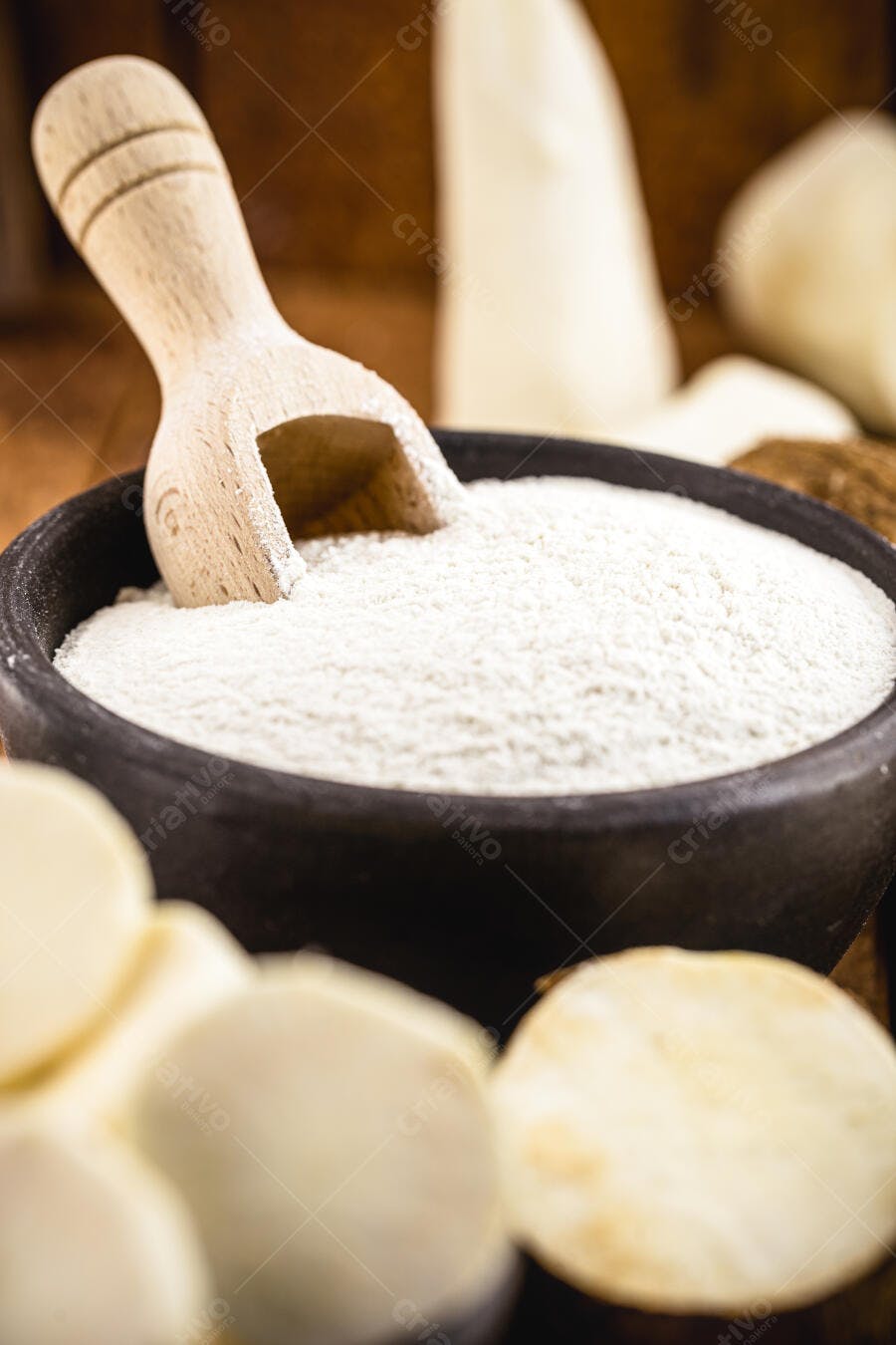 Farinha de tapioca branca em tigela rústica com colher de pau e mandioca