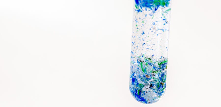 Tubo de ensaio com microplásticos azuis e verdes pesquisa ambiental