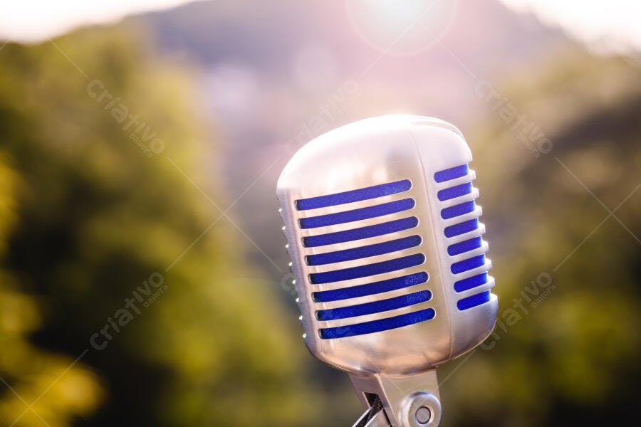 Microfone vintage prateado com detalhes azuis em cenário natural ensolarado