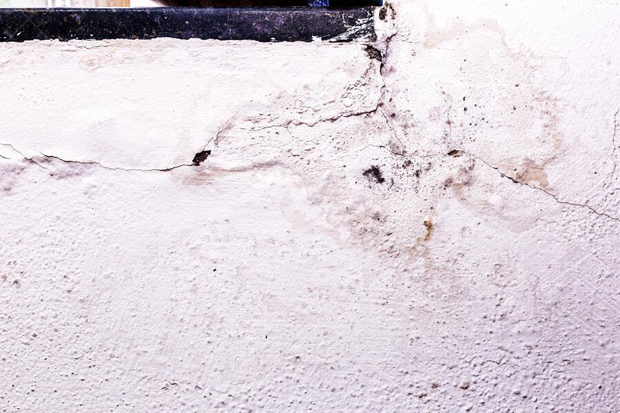 Parede branca com rachaduras e manchas de mofo e umidade