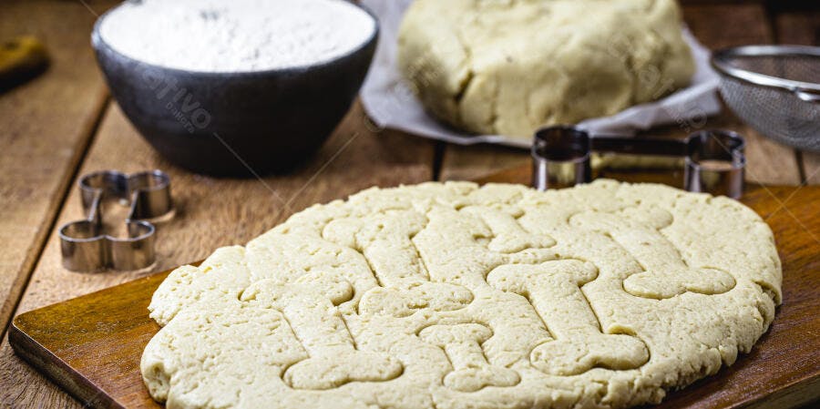 Massa de biscoito de osso para cão na bancada de madeira com farinha