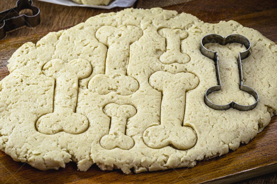 Massa de biscoito em forma de osso para cães na tábua de madeira