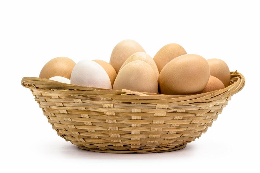 Ovos de galinha marrons e brancos frescos em cesta de vime sobre fundo branco