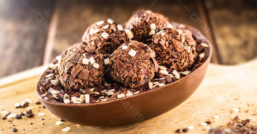 Ovo de Páscoa de chocolate com brigadeiros granulados em mesa de madeira rústica