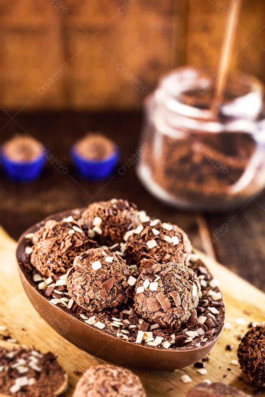 Ovo de Páscoa de chocolate escuro recheado com brigadeiros e flakes em tábua de madeira