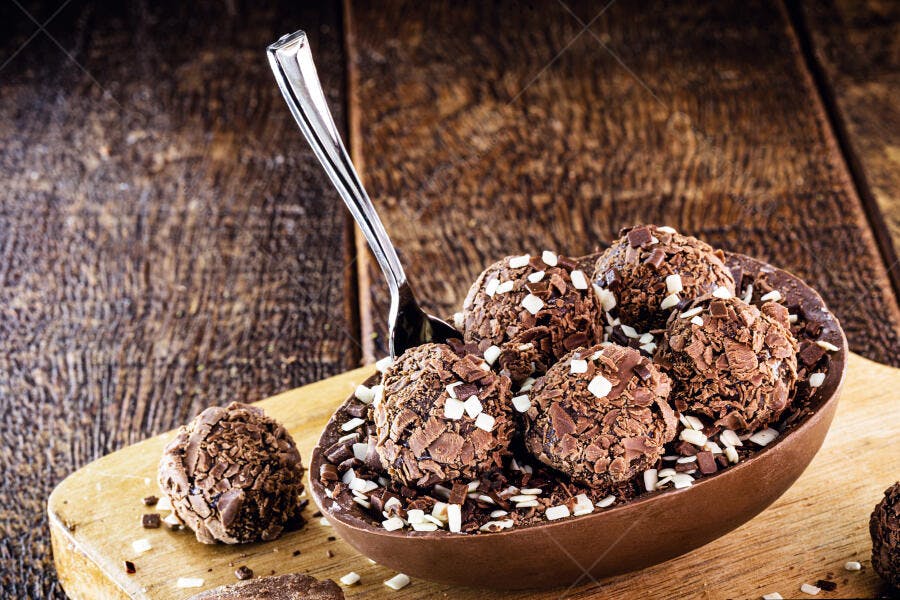 Ovo de Páscoa de chocolate recheado com brigadeiros e colher em fundo rústico
