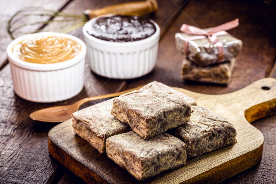 Paçocas doces de amendoim com açúcar e doces brasileiros em mesa rústica