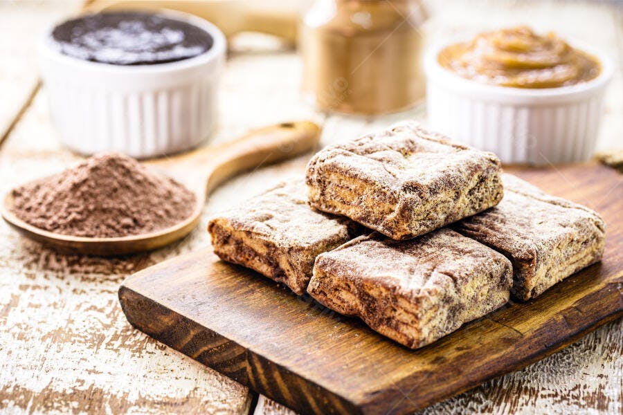 Doces de amendoim retangulares em tábua rústica com cacau e brigadeiro