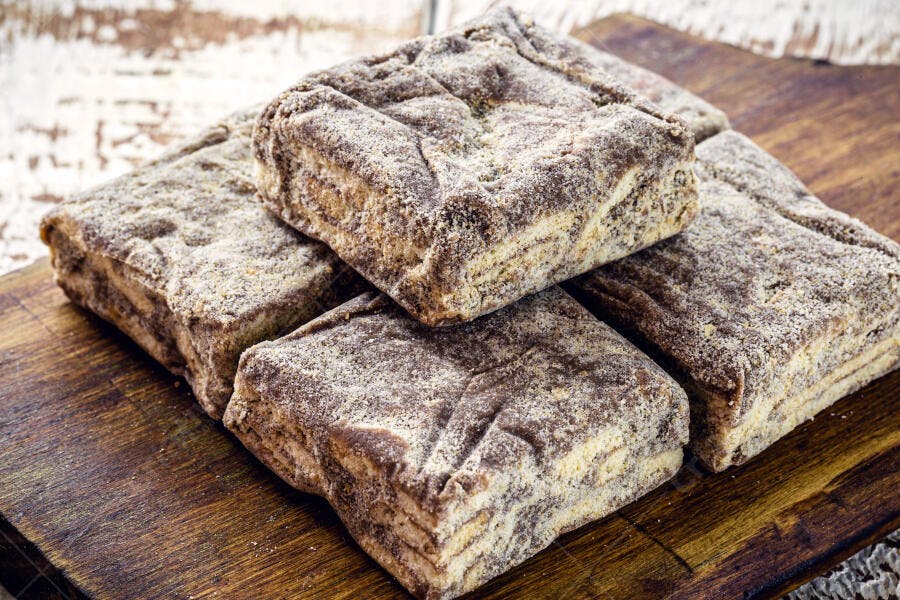 Pães de mel quadrados com açúcar de confeiteiro em tábua de madeira rústica