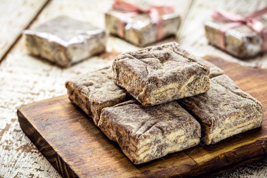 Doces quadrados de chocolate polvilhados em tábua de madeira com presentes