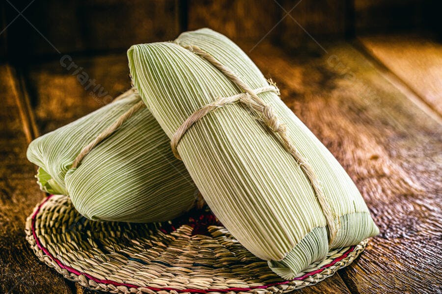 Pamonhas tradicionais de milho verdes sobre mesa de madeira rústica com palha