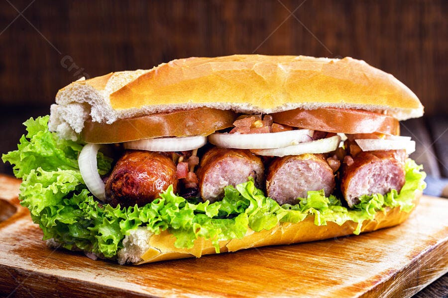 Sanduíche de linguiça no pão francês com alface tomate e cebola em tábua de madeira