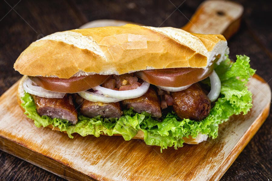 Sanduíche de linguiça pão francês com alface, tomate e cebola em tábua rústica